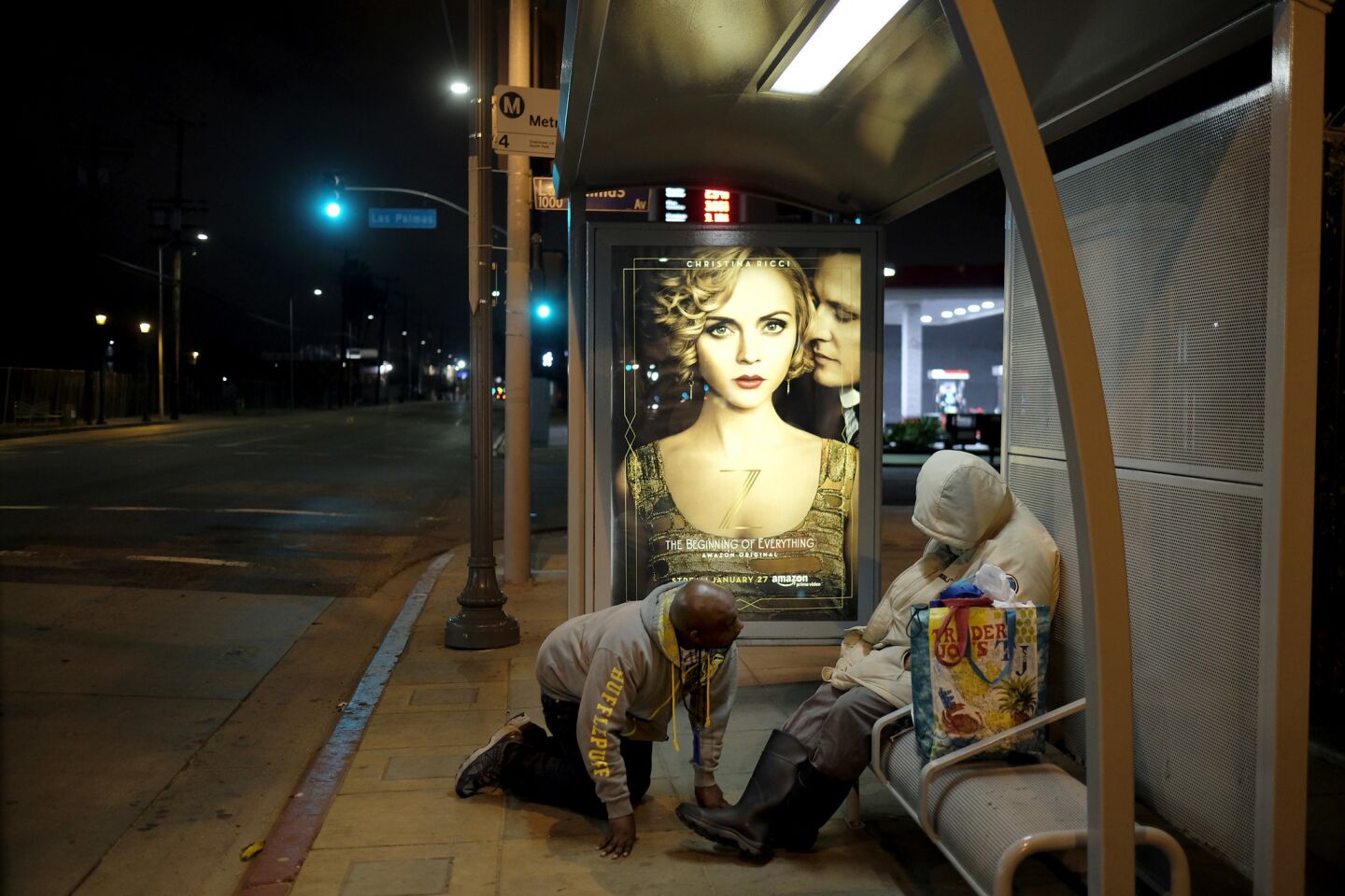 Housing Works caseworker Anthony Ruffin kneels as he checks on a homeless woman sleeping on a bus bench in Hollywood.