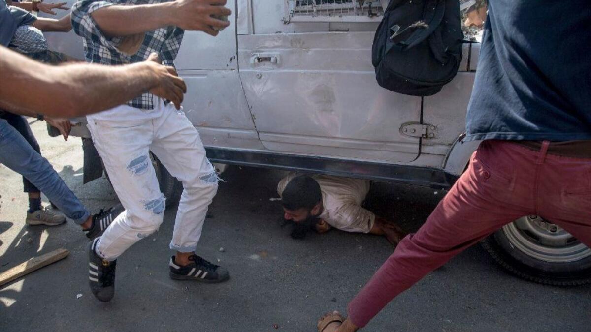 Kashmiri protesters surround an Indian paramilitary vehicle that is running over a man in Srinagar on June 1, 2018.