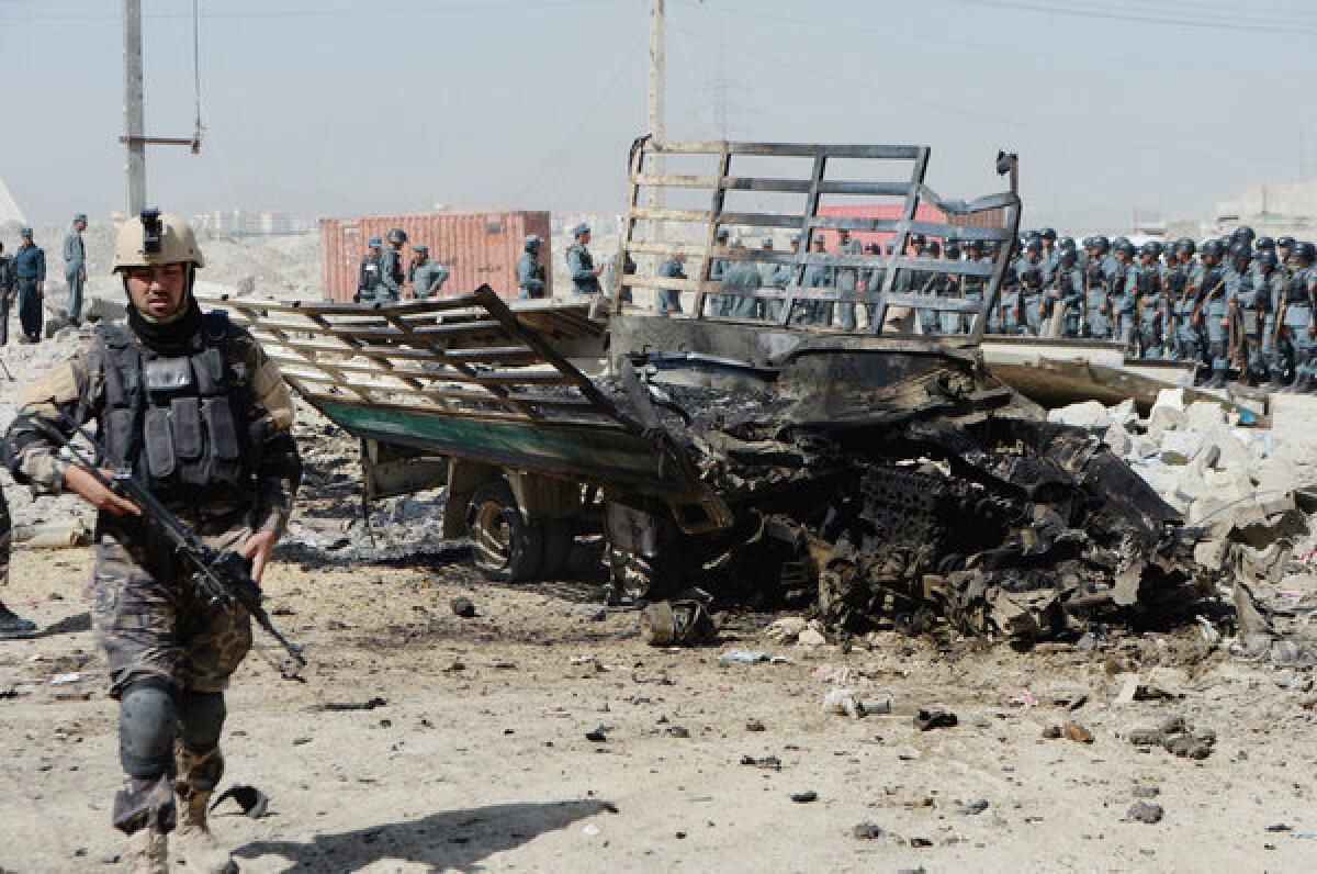 An member of the Afghan security forcse walks at the site of a suicide attack near the airport in Kabul.