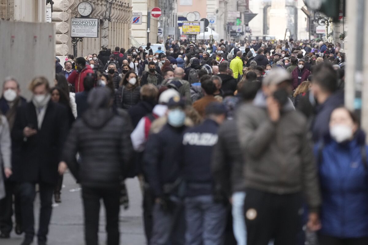 FILE - People stroll along the Via del Corso avenue in Rome, on Jan. 5, 2022. New coronavirus restrictions have gone into effect in Italy that amounted to a near-lockdown for the unvaccinated. As of Monday, proof of vaccination or a recent infection is required to access public transport, coffee shops and a host of other activities.The new “super” health pass requirement, which eliminates the ability to access services with just a negative test, coincided with the return to work and school for many Italians after the Christmas and New Year holiday. (AP Photo/Gregorio Borgia)