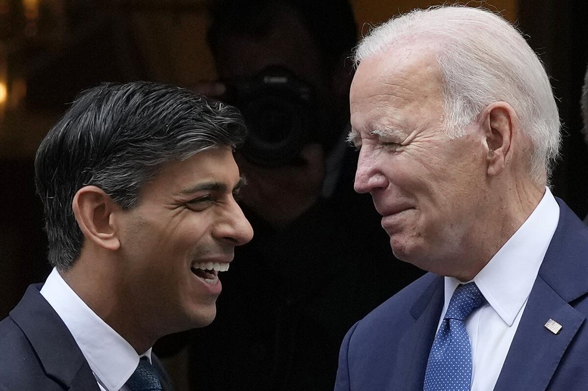 President Biden and British Prime Minister Rishi Sunak face each other and smile.