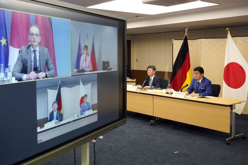 Japanese Foreign Minister Toshimitsu Motegi, second from right, and Defense Minister Nobuo Kishi, right, attend a video conference with German Foreign Minister Heiko Maas, top left on screen, and German Defense Minister Annegret Kramp-Karrenbauer, top right on screen, at Foreign Ministry in Tokyo during their "2 plus 2" ministerial meeting Tuesday, April 13, 2021. (Frank Robichon/Pool Photo via AP)