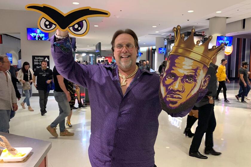 Gary Martin Zelman poses with two of his signs during the Lakers’ season-opening game against the Clippers at Staples Center on Oct. 22, 2019.