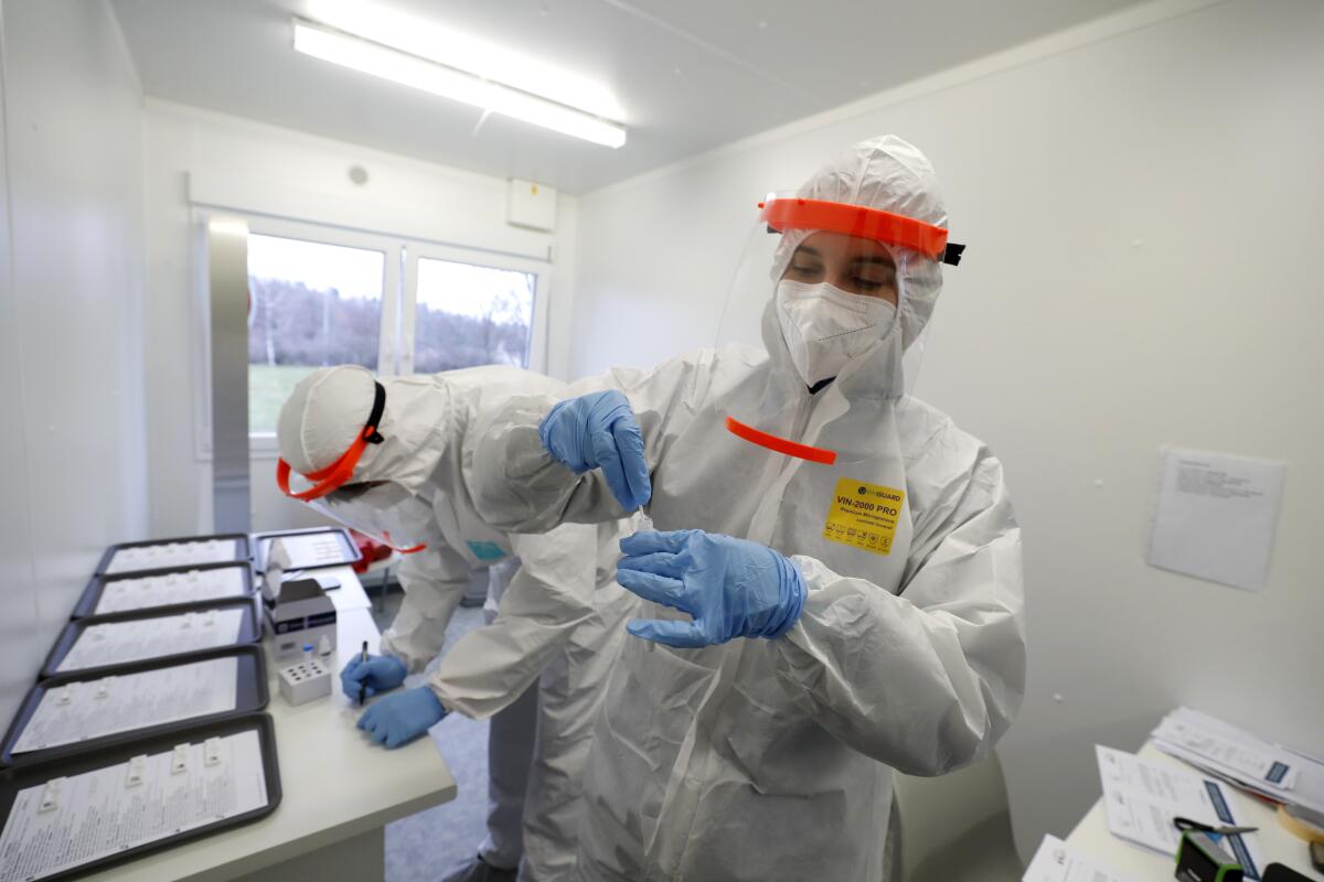 FILE- Medical workers examine the rapid antigen tests for the coronavirus in Prague, Czech Republic, Wednesday, Dec. 16, 2020. Czech Republic's Health Minister Vlastimil Valek said Friday Jan. 14, 2022 that the new Czech government will allow some people who have been tested positive for the coronavirus to keep working, an extraordinary measure to ease possible staff shortages caused by an anticipated surge of the omicron variant. The measure, which was used during the previous coronavirus waves, would only apply for workers at the health care system and in nursing homes who have no symptoms of COVID-19. (AP Photo/Petr David Josek, file)