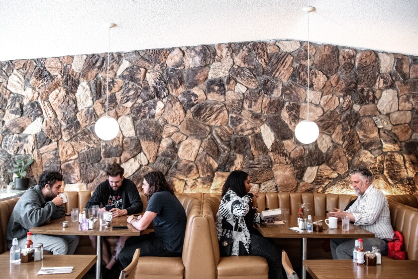 Customers sit in tan booths along a flagstone wall.