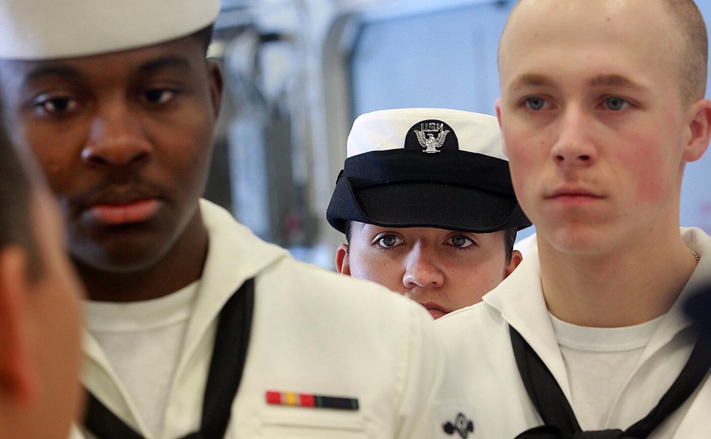 Airman Amanda Garcia, center, looks over the shoulders of fellow airmen Deldrick Lee and Jeff Heatley, while listening to their chief, aboard the USS America.