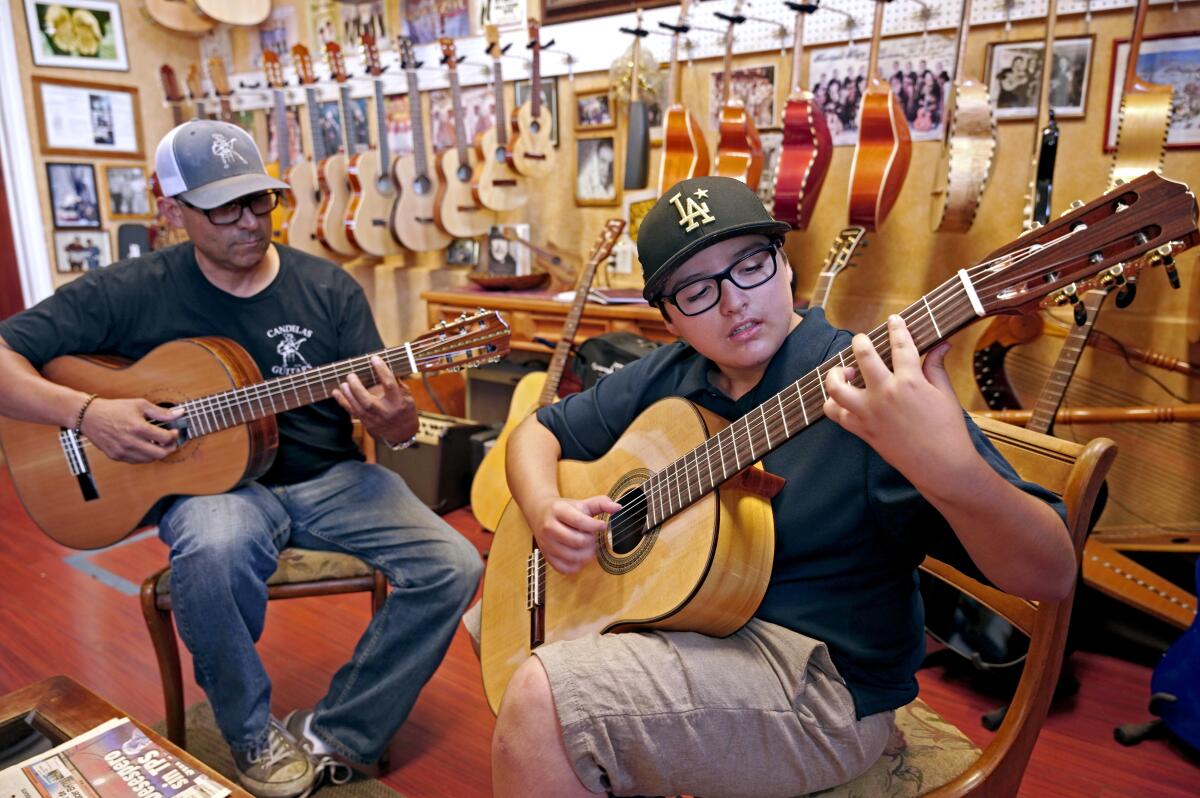 Candelas Guitars owner Tomas Delgado, left, keeps an eye on student Eloy Gonzalez.