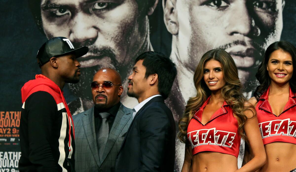 Floyd Mayweather Jr., left, and Manny Pacquiao face off in front of promoter Leonard Ellerbe at the conclusion of their news conference on Wednesday at the MGM Grand Hotel.