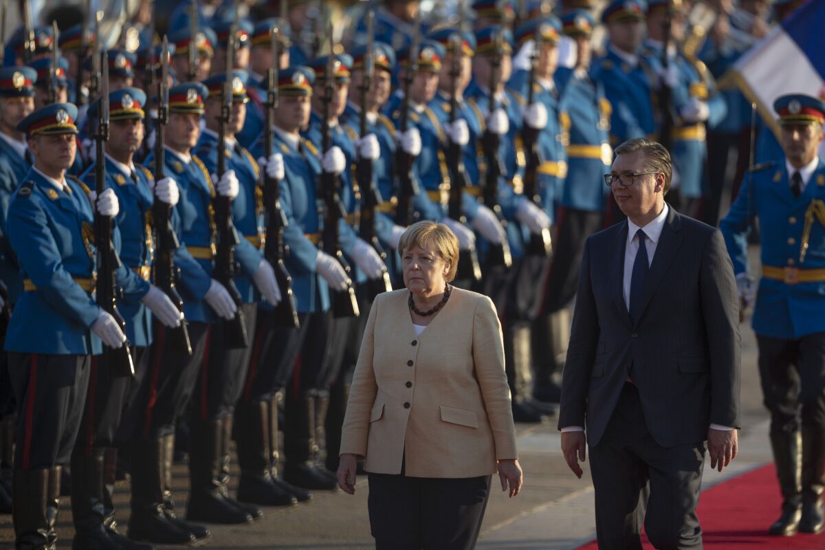 German Chancellor Angela Merkel, center, walks past honor guards while being accompanied by Serbia's president Aleksandar Vucic, front right, in Belgrade, Serbia, Monday, Sept. 13, 2021. Merkel is on a farewell tour of the Western Balkans, as she announced in 2018 that she wouldn't seek a fifth term as Germany's Chancellor. (AP Photo/Marko Drobnjakovic)