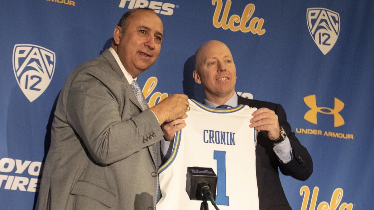 UCLA athletic director Dan Guerrero, left, and new men's basketball coach Mick Cronin hold up a jersey during Cronin's introductory news conference Wednesday.