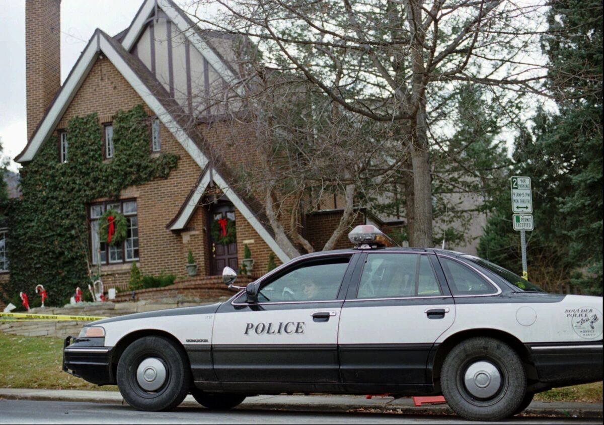 FILE - In this Jan. 3, 1997, file photo, a police officer sits in her cruiser outside the home in which 6-year-old JonBenet Ramsey was found murdered in Boulder, Colorado on Dec. 26, 1996. The father of JonBenet Ramsey, John Ramsey, is supporting an online petition asking Colorado Gov. Jared Polis to transfer DNA testing in the case away from the Boulder Police Department to an outside agency. (AP Photo/David Zalubowski, File)