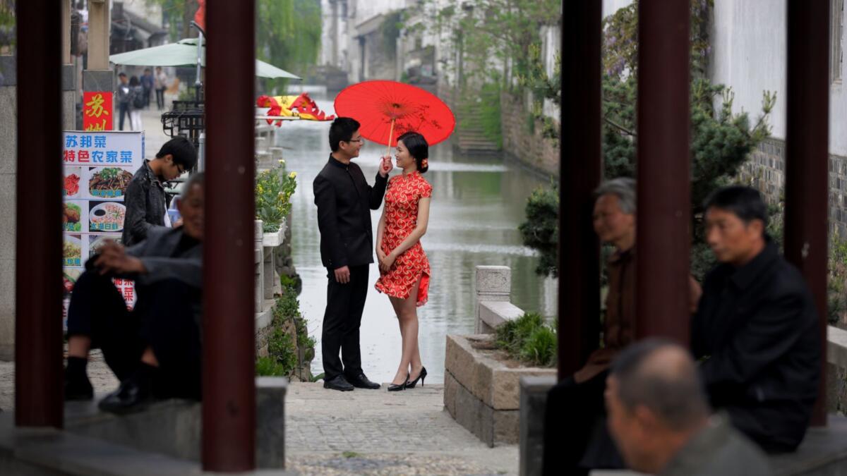 A bride and groom, dressed a traditional costume, pose for wedding photos in Suzhou, China, where a trial with the social credit system Osmanthus is underway.
