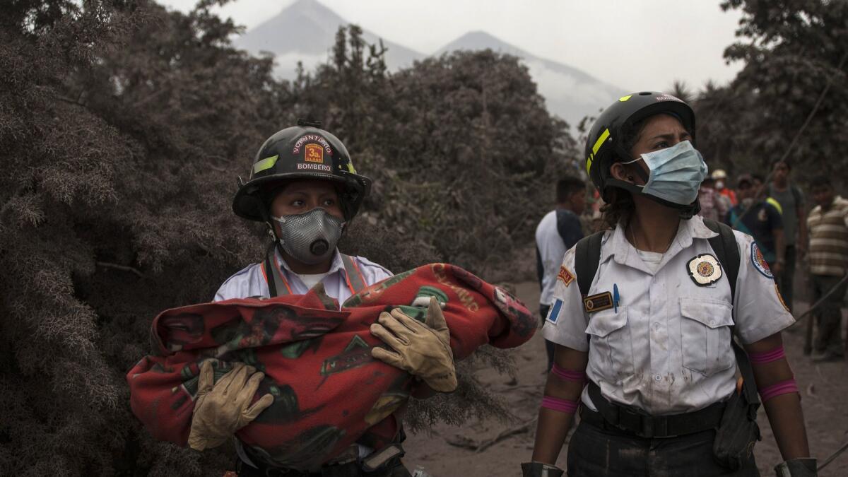 A firefighter carries the body of a child recovered near the volcano in Escuintla, Guatemala, on June 4, 2018.