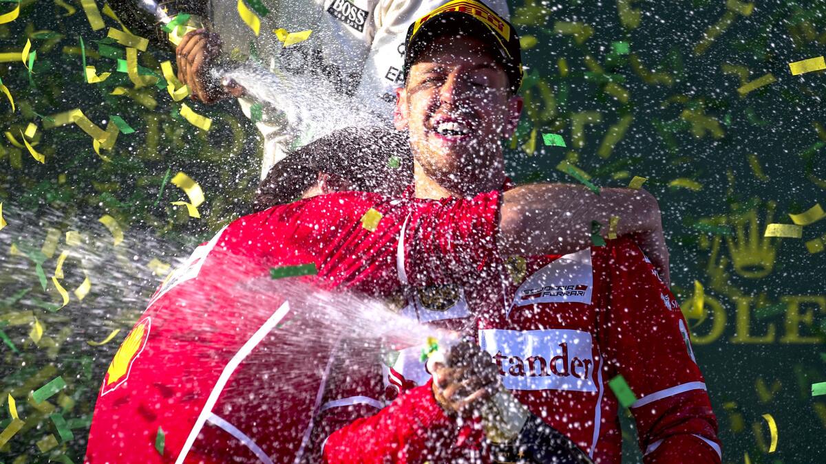 Formula One driver Sebastian Vettel celebrates on the podium with Luigi Fraboni, Ferrari's head of trackside operations, after winning the Australian Grand Prix on Sunday. (Diego Azubel / EPA)