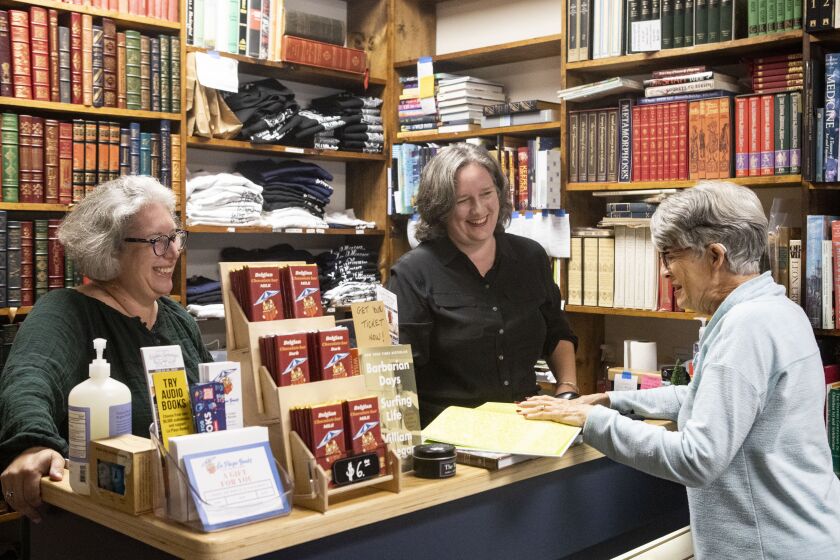San Diego, CA - November 18: La Playa Books staff member Marianne Reiner, far left, and manager Amy Hesselink, far right, help Marilyn Daniels, of San Diego, with a purchase at the store on Friday, Nov. 18, 2022 in San Diego, CA. (Meg McLaughlin / The San Diego Union-Tribune)
