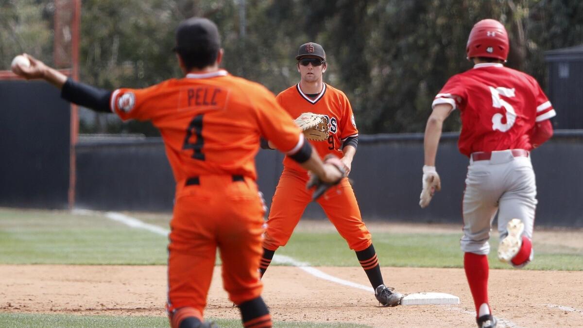 Huntington Beach High's Josh Hahn (9) waits as starting pitcher Edward Pelc (4) throws Los Alamitos' Ethan Overby (5) out at first base in the third inning of a Sunset League game on May 2.