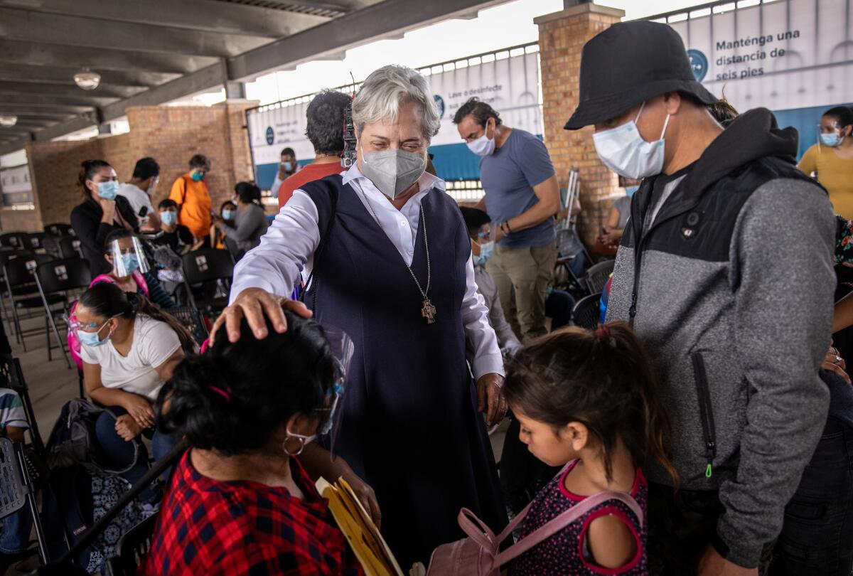 Sister Norma Pimentel hold her hand on the head of a migrant as she addresses a group of asylum seekers.