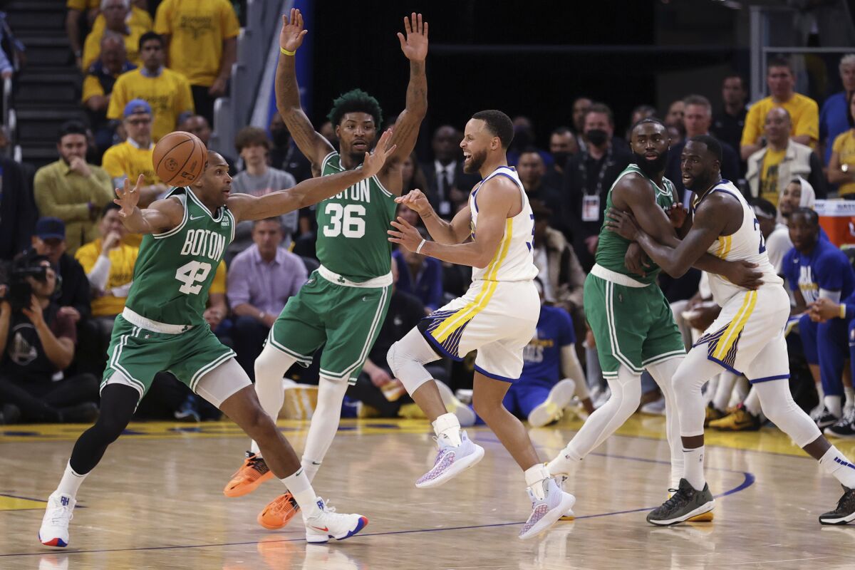 Golden State Warriors' Stephen Curry passes the ball past Boston Celtics' Al Horford (42) and Marcus Smart during the fourth quarter of Game 1 of basketball's NBA Finals, Thursday, June 2, 2022, in San Francisco. (Strazzante/San Francisco Chronicle via AP)
