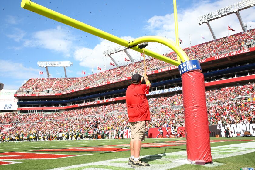 Honey bees are swept from an upright at the beginning of the NFL football game between the Tampa Bay Buccaneers and the Green Bay Packers on Sunday, Sept. 25, 2022, at Raymond James Stadium in Tampa, Fla. (Douglas R. Clifford/Tampa Bay Times via AP)