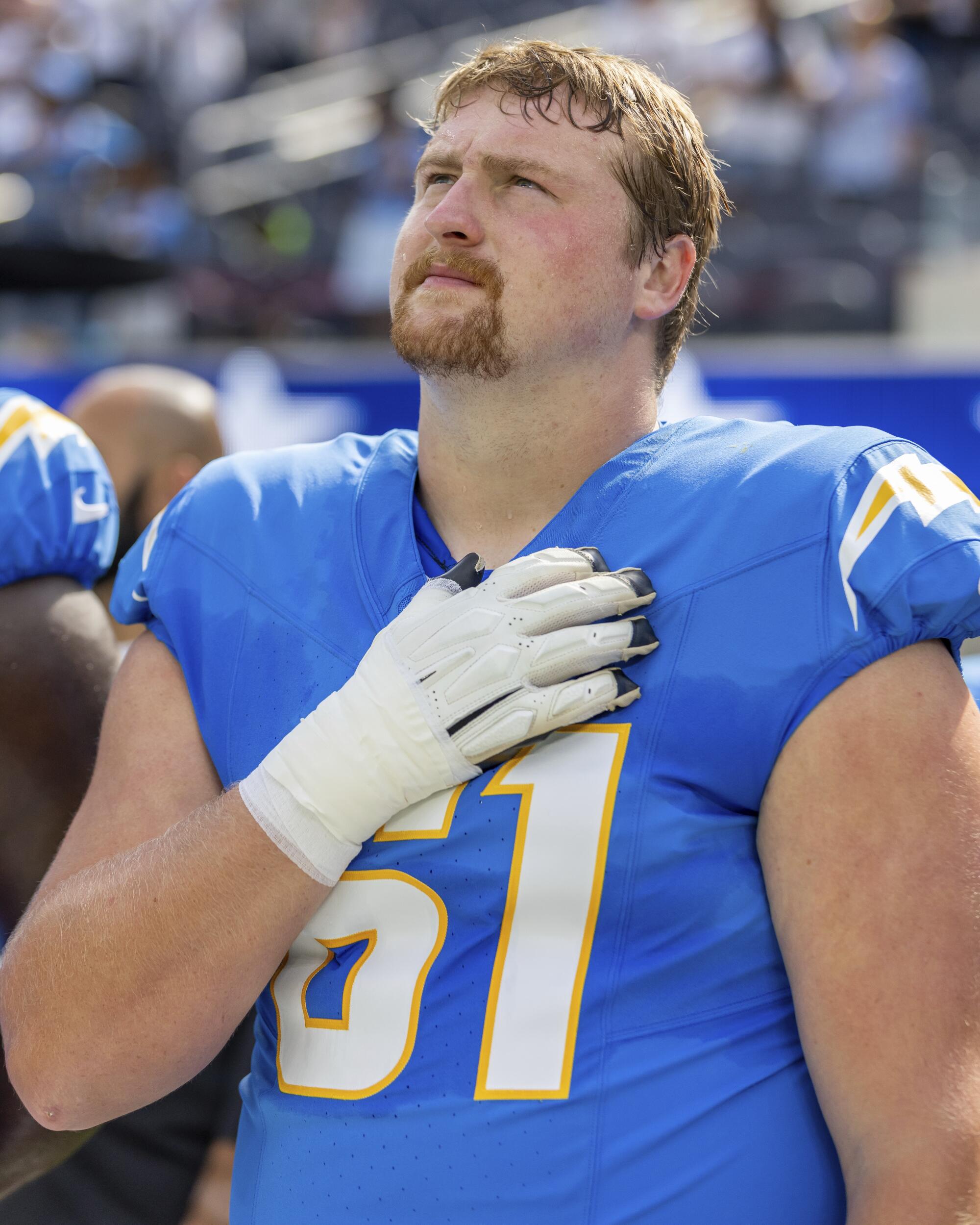 Chargers guard Karsen Barnhart (61) stands for the National Anthem with his hand on his heart.