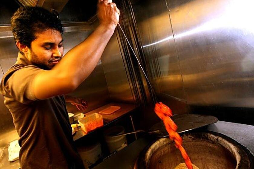 Mutiara Food & Market's owner Myo Aung prepares tandoori chicken.