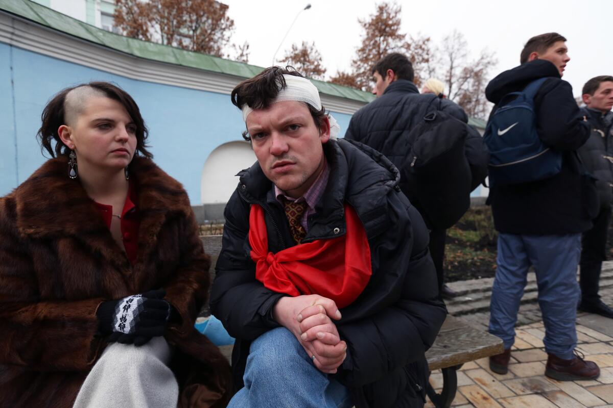 Nelli Didenko and Igor Mitrov sit on the grounds of St. Michael's Cathedral in downtown Kiev on Saturday. Both say they were injured when police used truncheons to clear nearby Independence Square early in the morning.