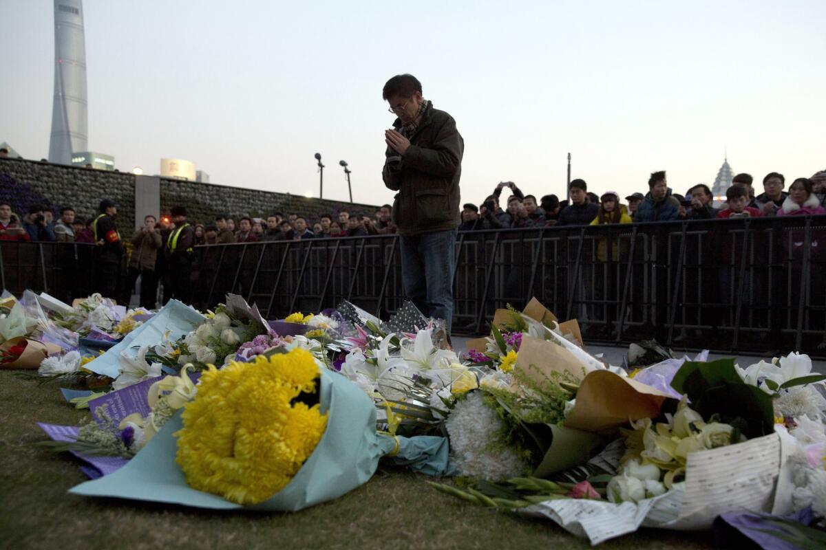 A man prays on Jan. 1 after laying flowers at the site of a New Year's Eve deadly stampede in Shanghai, China. Shanghai sacked four top district officials for insufficient preparation and response to the stampede that killed 36 people, the city government announced Jan. 21.