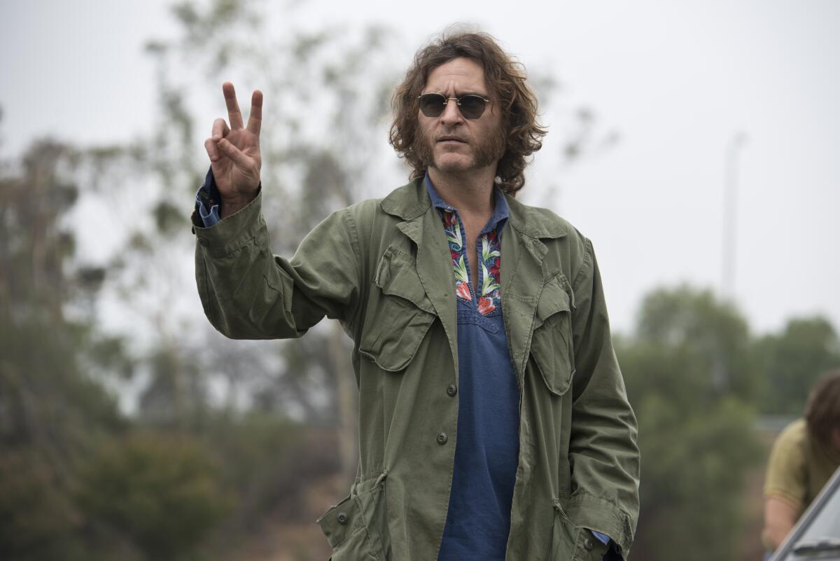 Joaquin Phoenix flashes a peace sign, man