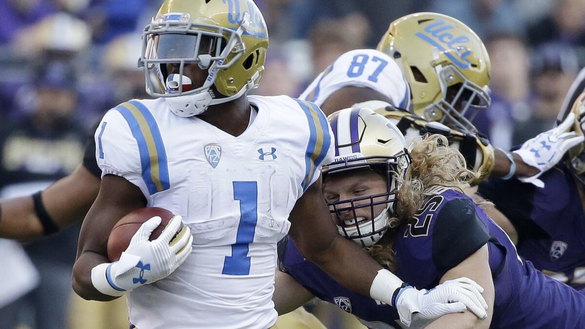 UCLA's Soso Jamabo (1) carries the ball as Washington's Ben Burr-Kirven moves in in the first half of an NCAA college football game Saturday, Oct. 28, 2017, in Seattle. (AP Photo/Elaine Thompson)