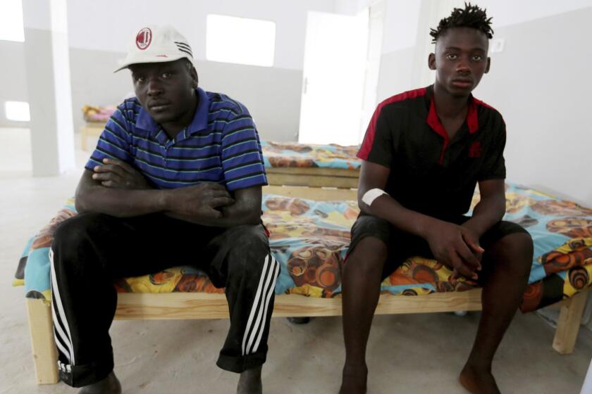 An unidentified Malian survivor, right, of a shipwreck sits in the Red Crescent center of Zarzis, southern Tunisia, Thursday, July 4, 2019. The U.N. migration agency says a boat carryinsg 86 migrants from Libya sank in the Mediterranean overnight, and just three people on board survived, with 82 missing. The shipwreck late Wednesday off the Tunisian city of Zarzis came a day after a deadly airstrike on a Libyan detention center that killed at least 44 migrants. (AP Photo/Sami Jelassi)