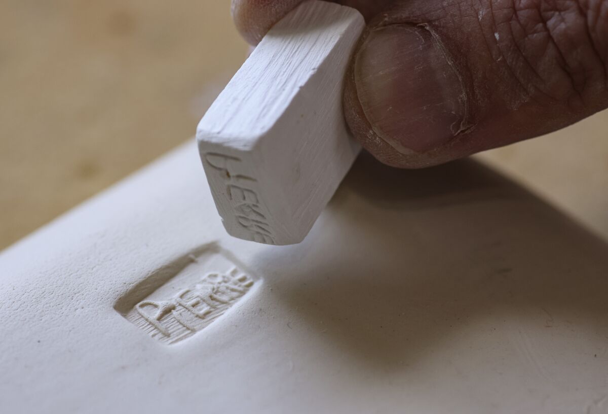 Bounaud presses his logo stamp onto the clay that will become one of his food-grade small plates.