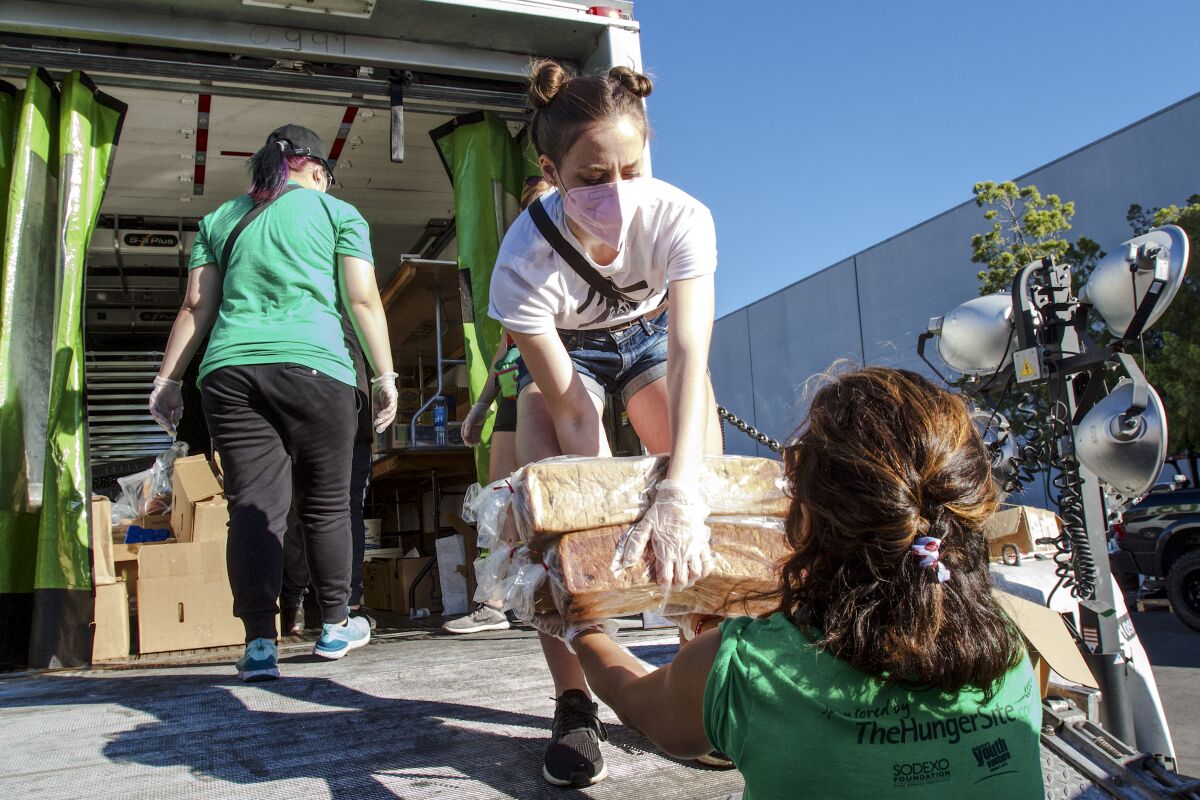 Three women from the Food Recovery Network unload fresh, unopened food from the back of a refrigerated truck.