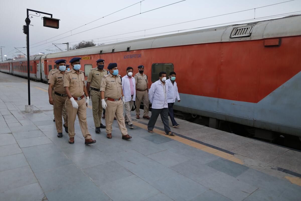 Railway officials walk through a deserted station platform in Prayagraj, India, on Tuesday.