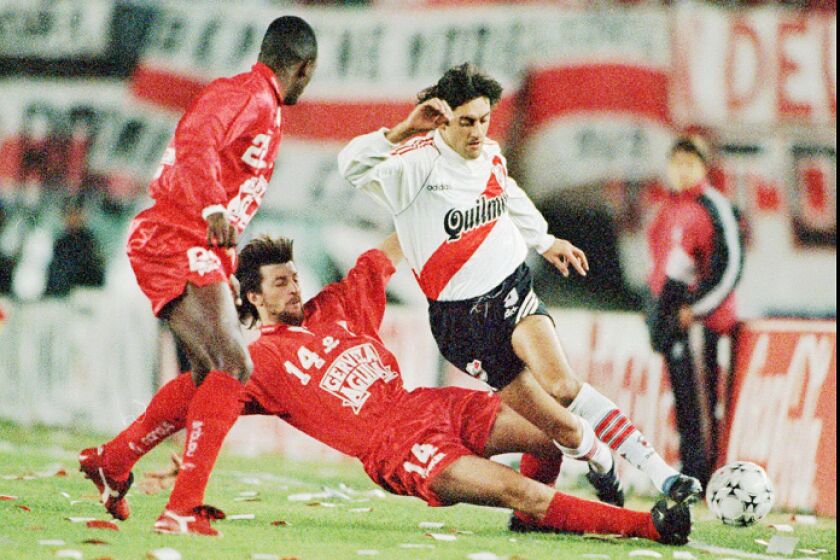 Uruguayan soccer ace Enzo Francescoli, who plays for Argentine River Plate, right, is fouled by Colombian Alfredo Berti of America de Cali as Colombian Carlos Asprilla looks on during the final game Wednesday, June 26, 1996, of the Libertadores of America soccer cup at River Plate stadium in Buenos Aires. (AP Photo/Eduardo Di Baia)