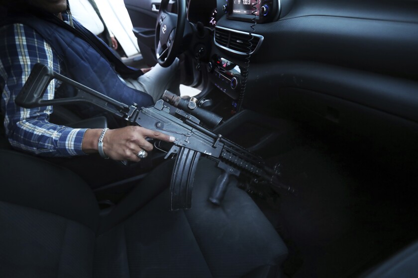 A driver holds an assault rifle