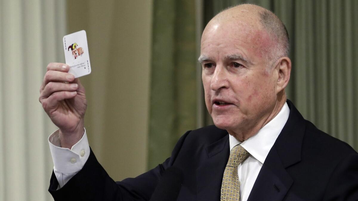 Gov. Jerry Brown displays a playing card with his dog, Sutter, on it during his State of the State speech in 2014. The cards, handed out to legislators, urged them to save — not spend — all of the growing tax revenues.