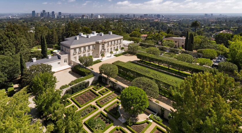 Aerial view of Chartwell mansion with manicured gardens and a city skyline in the background