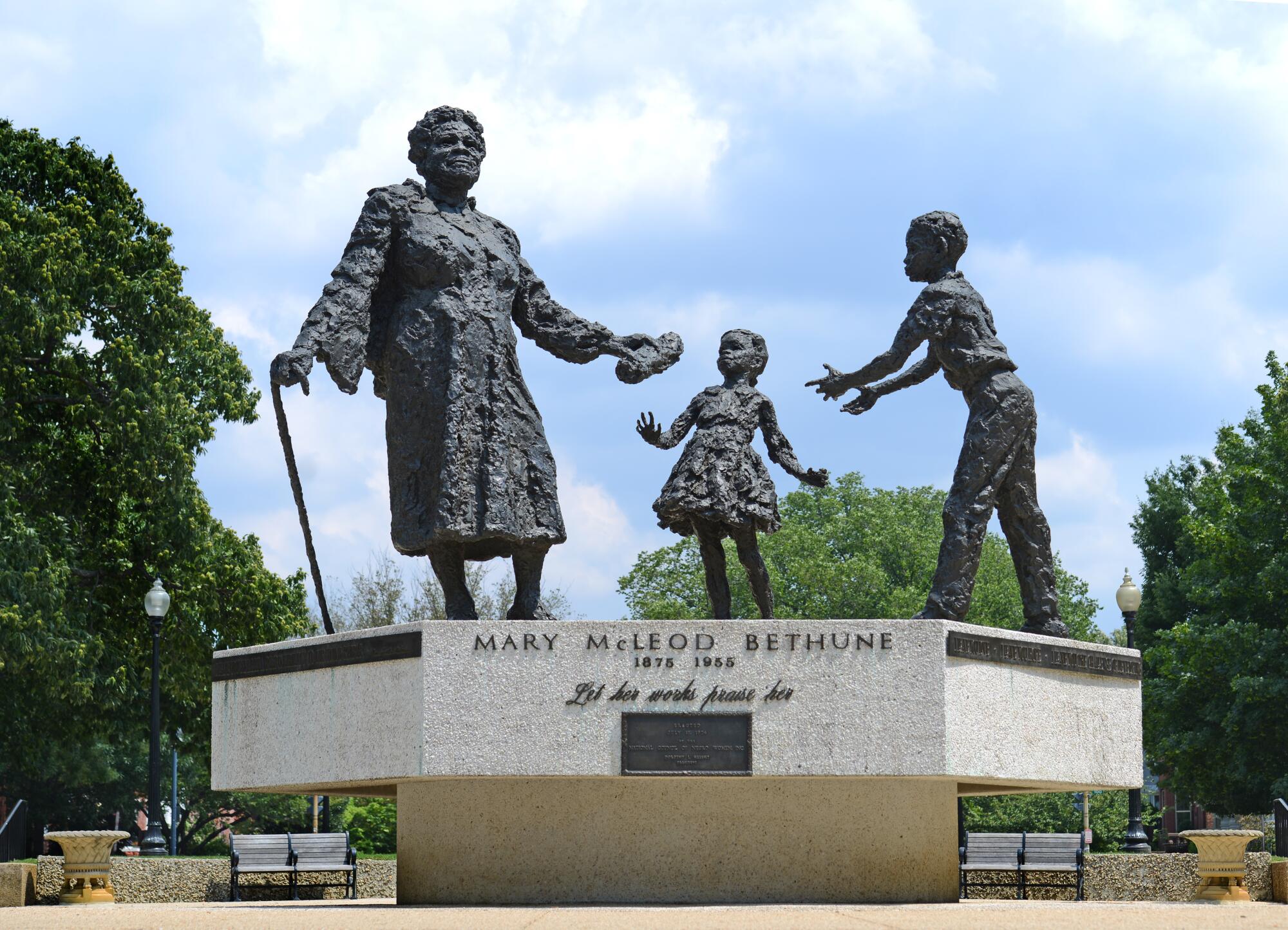 A bronze sculpture shows Black activist Mary McLeod Bethune passing a roll of papers to two young children.