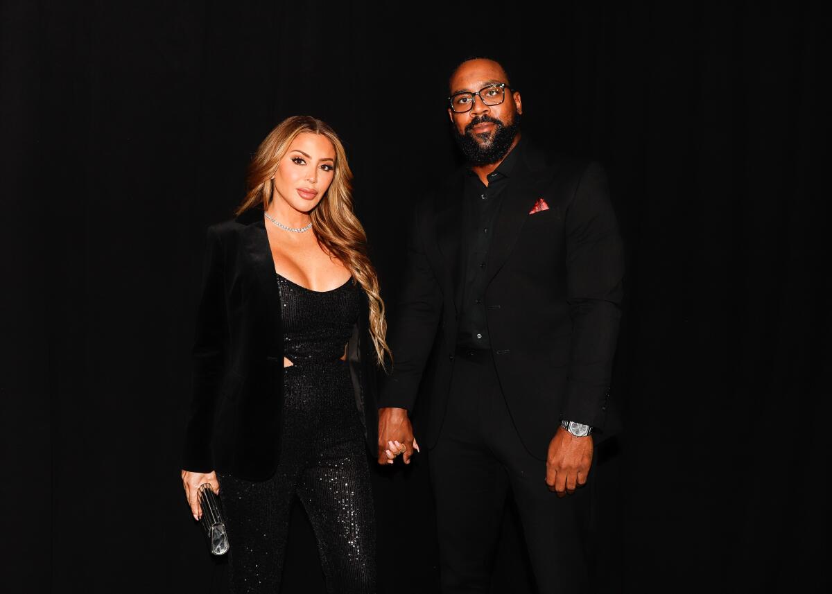 Larsa Pippen and Marcus Jordan hold hands in a dark picture while both wearing black outfits