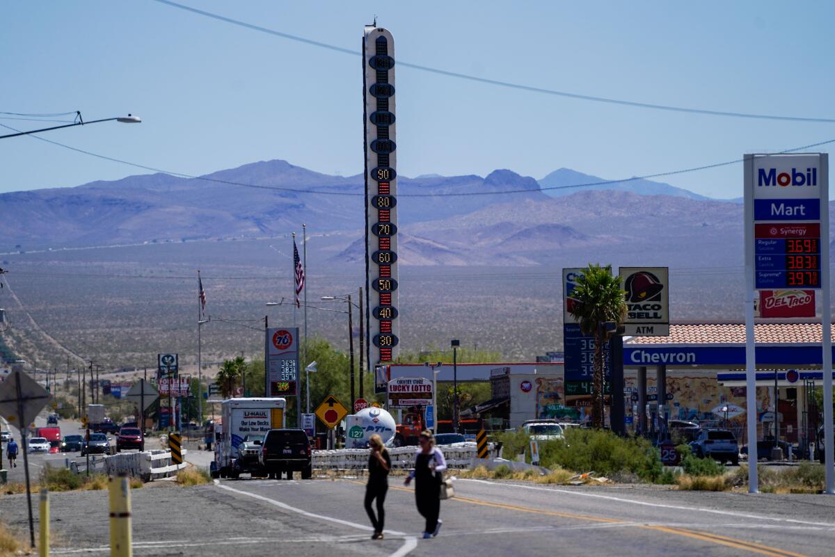 People cross Baker Boulevard, with the town's landmark 134-foot-tall electric thermometer in the background.