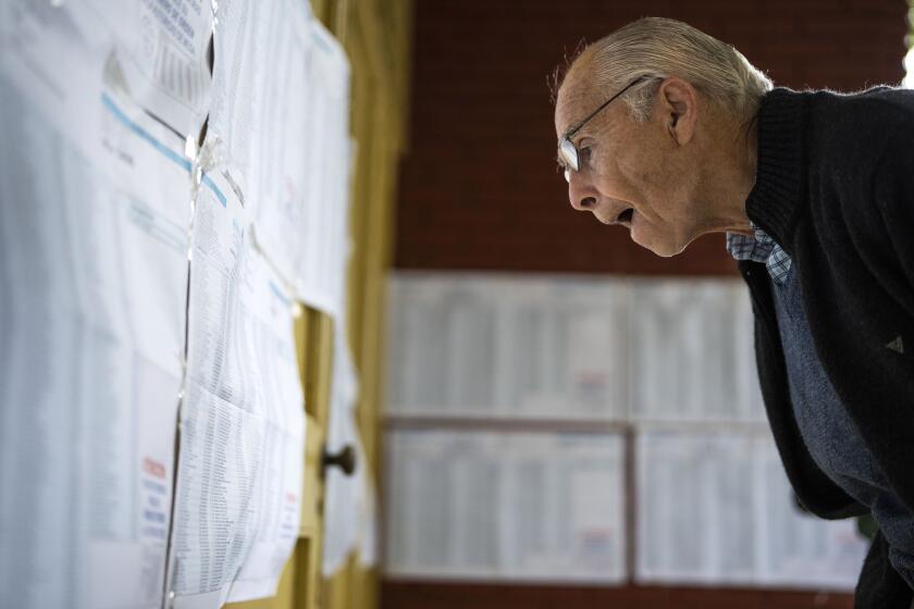 A man looks for his name in the electoral lists before voting during general elections in Buenos Aires, Argentina, Sunday, Oct. 22, 2023. (AP Photo/Rodrigo Abd)