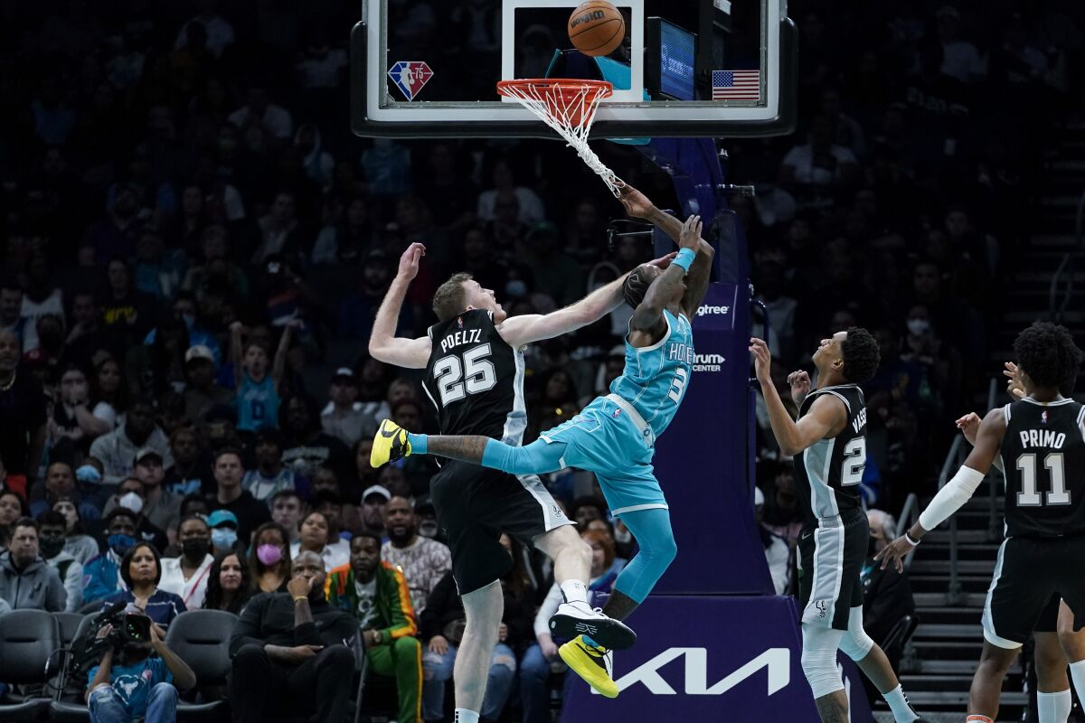 Charlotte Hornets guard Terry Rozier scores between San Antonio Spurs center Jakob Poeltl and guard Devin Vassell during the second half of an NBA basketball game on Saturday, March 5, 2022, in Charlotte, N.C. (AP Photo/Chris Carlson)