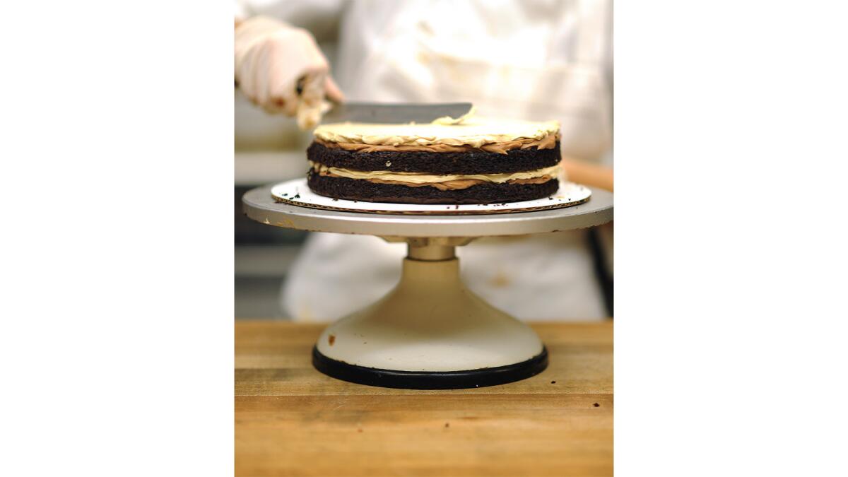 Espresso buttercream is spread onto the second layer of the cake.