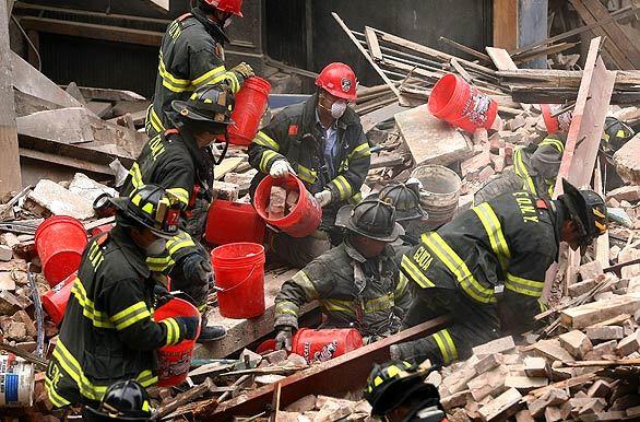 Firefighters sift through the rubble of a vacant five-story building that collapsed in lower Manhattan, leaving mounds of debris but apparently causing no injuries. The cause was not immediately determined.