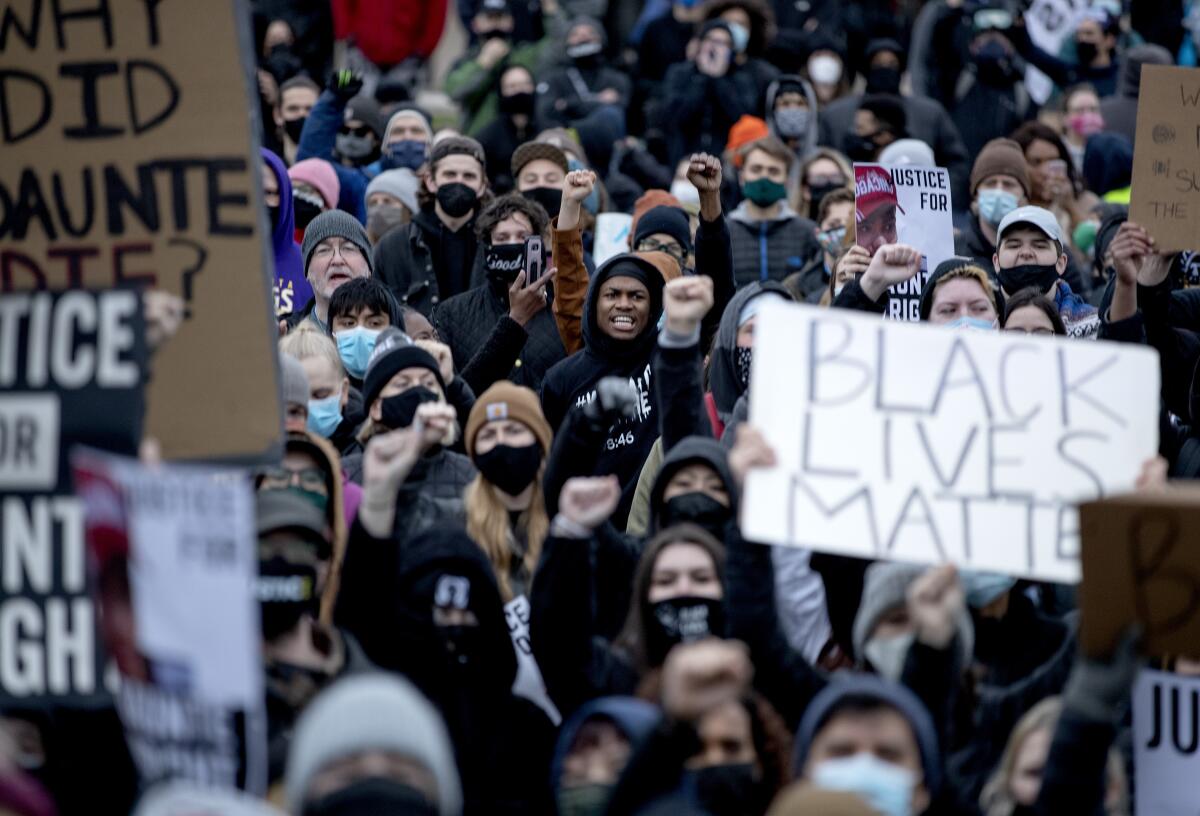 A crowd gathers outside with signs