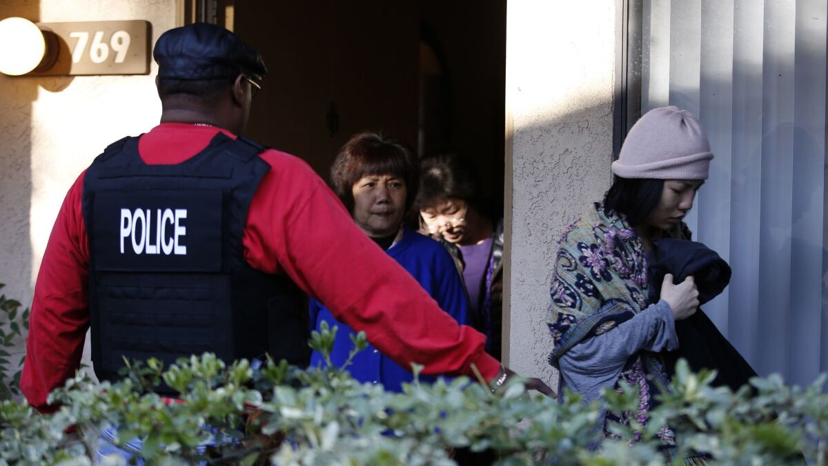 Federal agents escort residents from an apartment in Rowland Heights during a 2015 raid on an alleged "birth tourism" operation. On Thursday, prosecutors charged several people in such schemes, which bring pregnant women to the U.S to give birth.