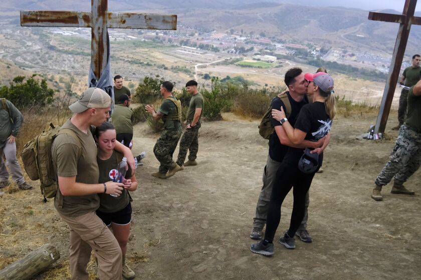 Navy Corpsman Brayden Benson, left and wife Navy Corpsman Morgan Benson take a breather after summiting First Sgt's Hill near Julianna Clemens who kissed her husband Marine Staff Sgt. Justin Clemens. Justin Clemens and Brayden Benson's father both saw action in Sangin, Afghanistan in 2011.