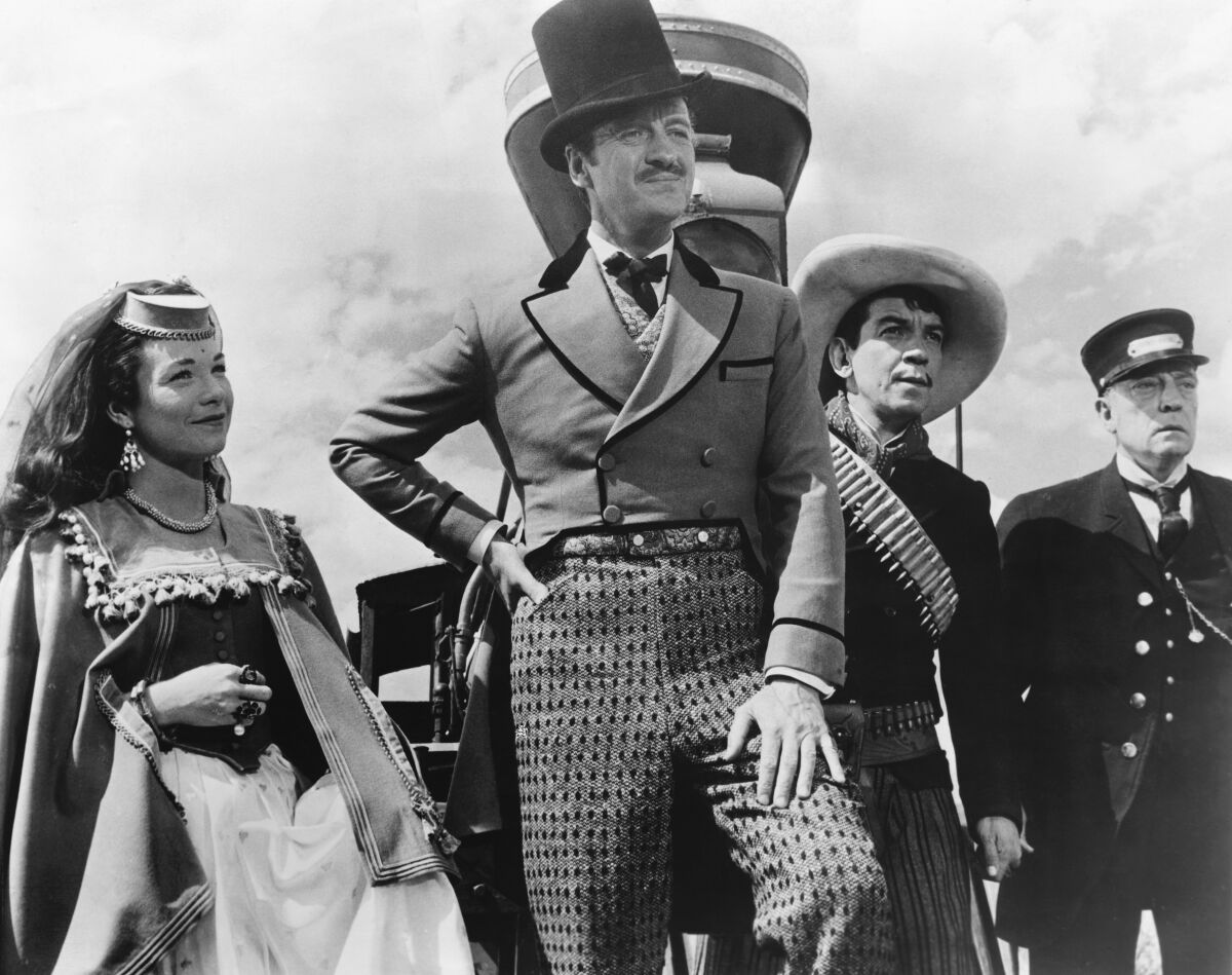 A woman and three men stand in front of a steam locomotive in “Around the World in 80 Days.”