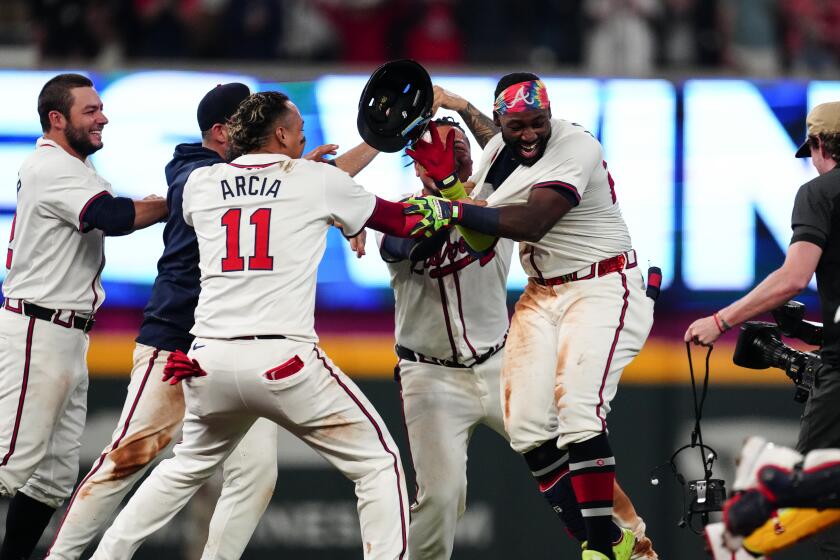 Atlanta Braves' Michael Harris II, right, is mobbed by teammates after driving in the game-winning run with a single in the 10th inning of a baseball game against the Miami Marlins Wednesday, April 24, 2024, in Atlanta. (AP Photo/John Bazemore)