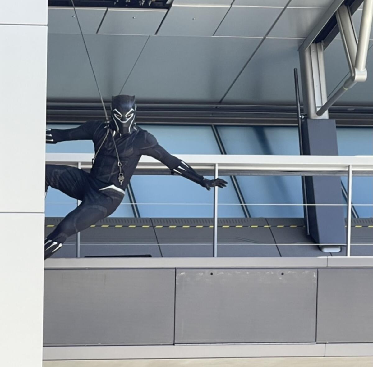 Black Panther is attached to a wire in front of a building.